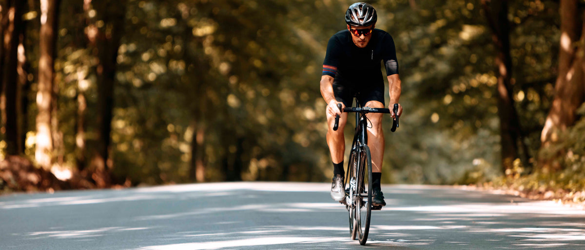 Cyclist riding a road bike along a tree-lined road