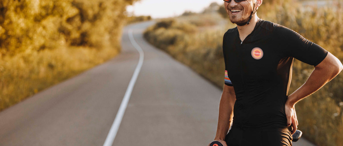 Smiling cyclist in a black jersey stopped on a country road at sunset